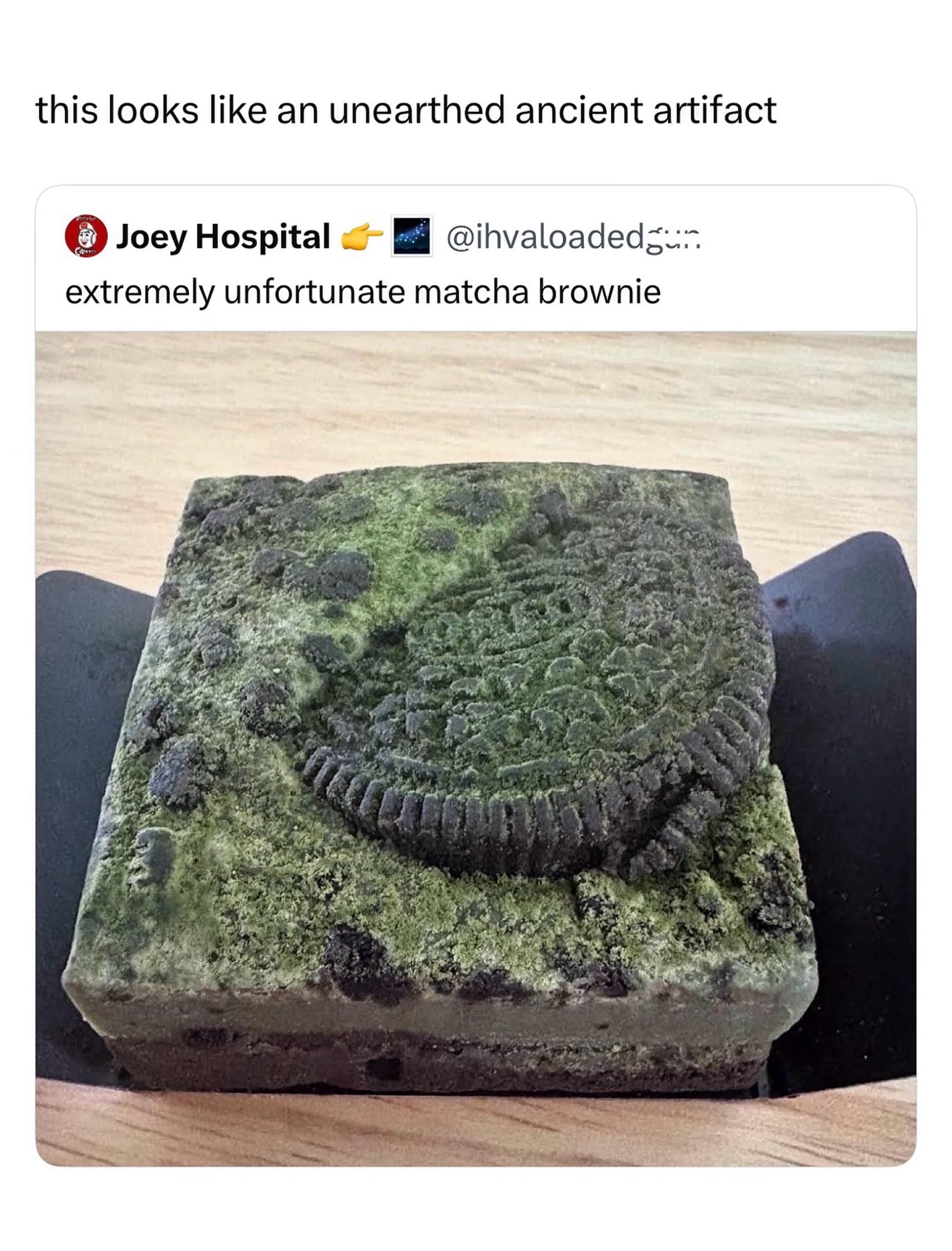 A culinary disaster photo shared in a meme dump showcasing an "extremely unfortunate matcha brownie" with an embedded cookie that looks exactly like a moss-covered, ancient stone artifact freshly unearthed from a damp archaeological dig site.
