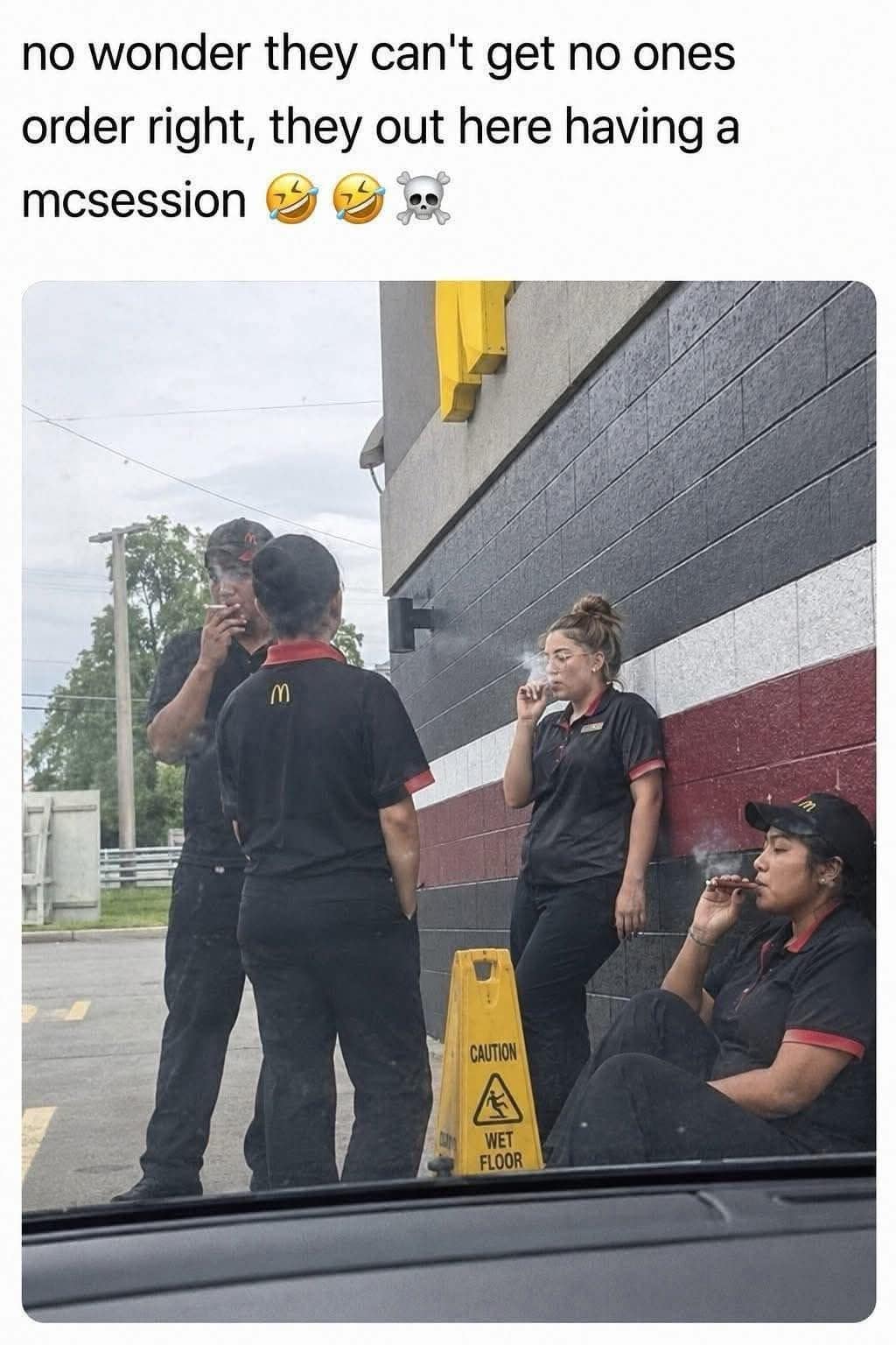 A funny meme inside a meme dump capturing four McDonald's employees in uniform gathered outside by a restaurant wall next to a wet floor sign, all intensely smoking cigarettes and cigars during a collective "McSession."
