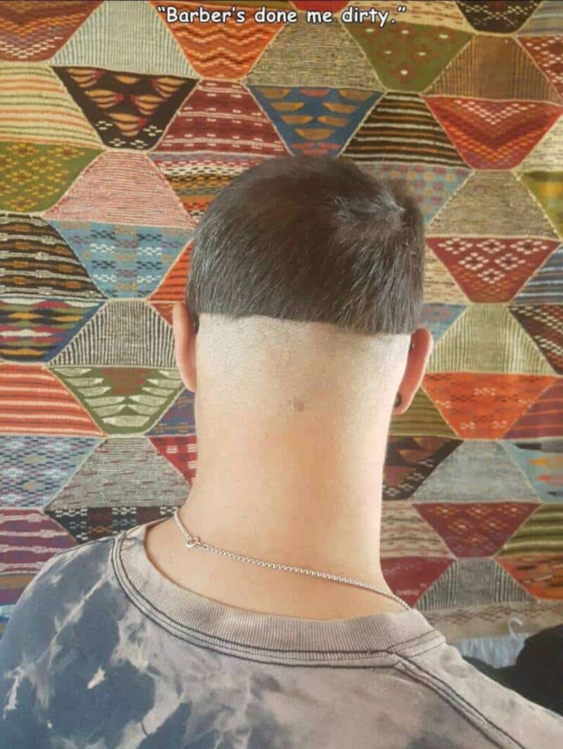 A catastrophic haircut disaster documented in an online meme dump captures a rear close-up of a guy's head showing an incredibly harsh, unblended undercut line slicing crookedly across his scalp under the text overlay, "Barber's done me dirty."