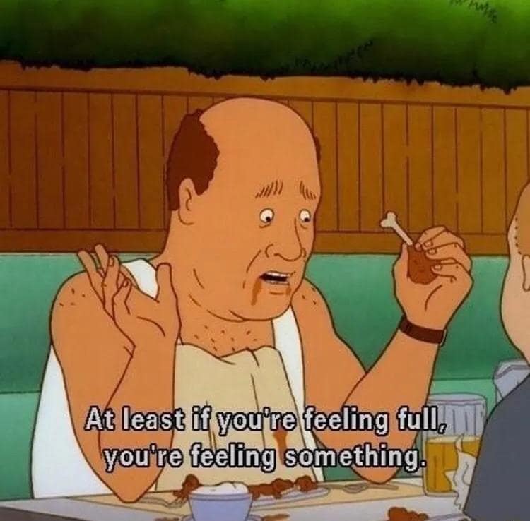 A screenshot from a hilarious meme showing Bill Dauterive from the animated series King of the Hill looking thoroughly depressed, tearful, and messy while holding up a clean chicken wing bone. The text overlay reads: "At least if you're feeling full, you're feeling something."