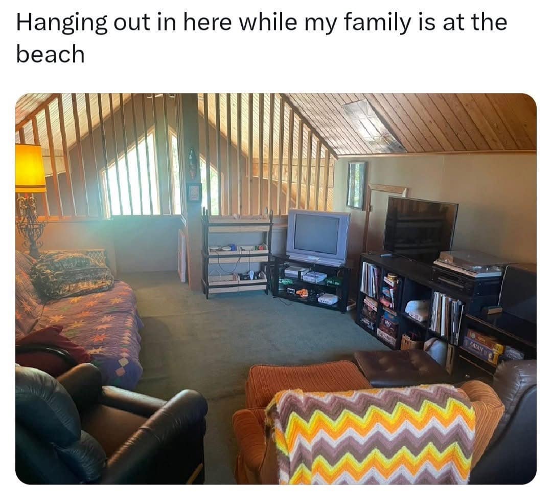 nostalgic funny meme shows a cozy old attic game room with the caption “Hanging out in here while my family is at the beach,” capturing the specific vacation joy of choosing vintage TVs, carpet, and air conditioning over sand, sunburn, and social expectations.