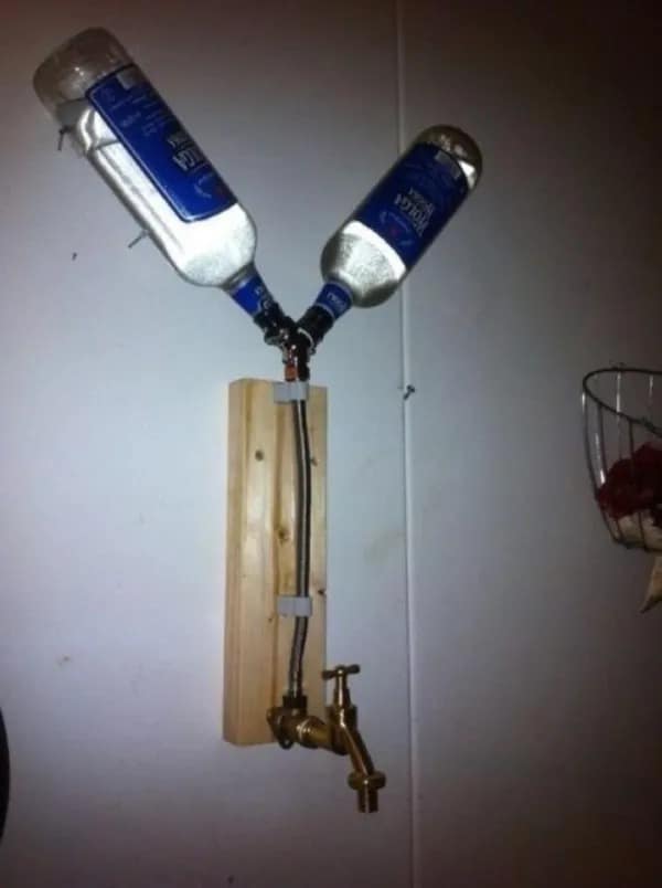 DIY alcohol tap dispenser system pictured in a funny meme dump setup, splitting two vodka bottles into a single brass water spigot.