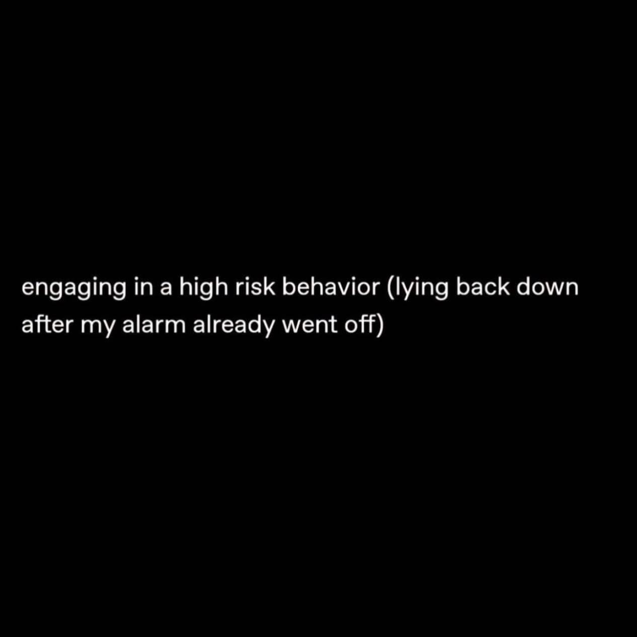 A minimalist text macro from a meme dump consisting of a plain black screen with crisp white text detailing a nearly universal daily struggle: "engaging in a high risk behavior (lying back down after my alarm already went off)."