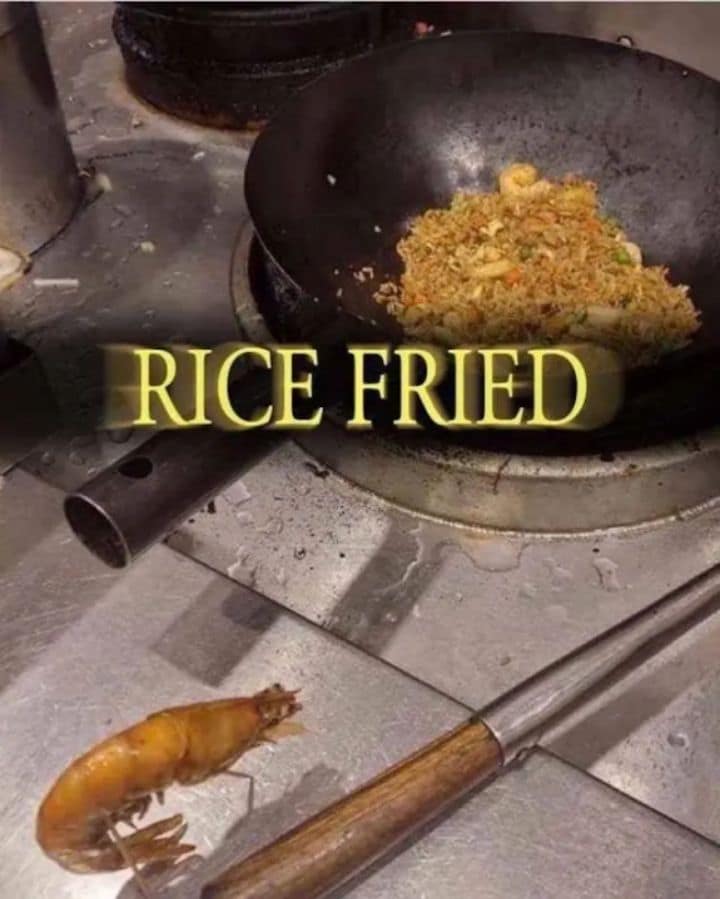 Gaming crossover memes snapshot showing a wok full of homemade shrimp fried rice with a golden, glowing Dark Souls styled typography overlay reading "RICE FRIED" as a lone shrimp sits defeated on the stainless steel kitchen counter.