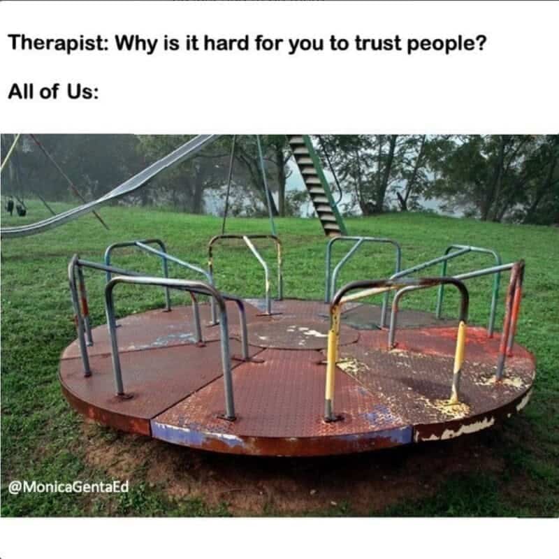 A playground-themed nostalgia meme showing a rusted, old-school heavy metal park merry-go-round platform spinning wheel, overlaid with an imaginary therapy session dialogue: "Therapist: Why is it hard for you to trust people? All of Us:".