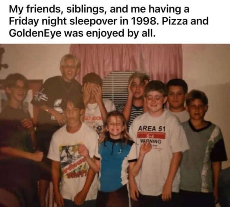 A heartwarming flash-photography nostalgia meme capturing a grainy group photo of kids at a Friday night home sleepover in 1998 wearing retro skate and Area 51 graphic tees, captioned to celebrate a night spent eating pizza and playing GoldenEye 007 on Nintendo 64.