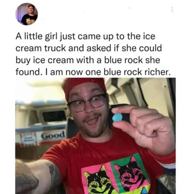A smiling ice cream truck driver proudly showing off a small blue rock traded for a treat.
