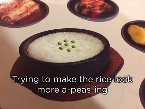 A restaurant menu graphic depicting a dark bowl of white rice, showing a comically lazy photoshop fail where seven bright green peas have been poorly copy-pasted on top in a flat, artificial circle with zero shadows or depth.