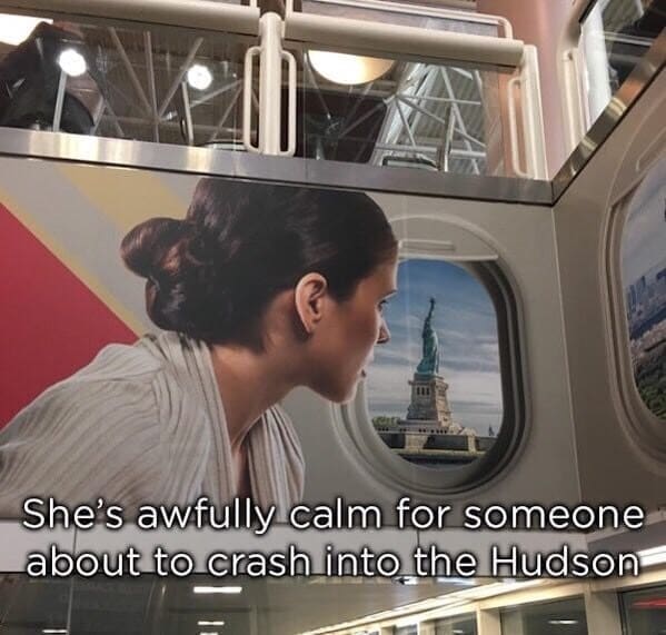 A large wall mural advertisement inside an airport terminal showing a woman looking out a commercial plane window, displaying a severe perspective photoshop fail where the Statue of Liberty is impossibly close to the glass at a terrifyingly low altitude.
