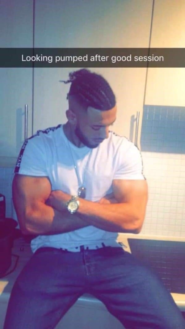 A gym enthusiast crossing his arms in a kitchen under the caption "Looking pumped," while the vertical lines of the white cabinets behind his arms are noticeably sucked inward from a body-shaping photoshop fail.
