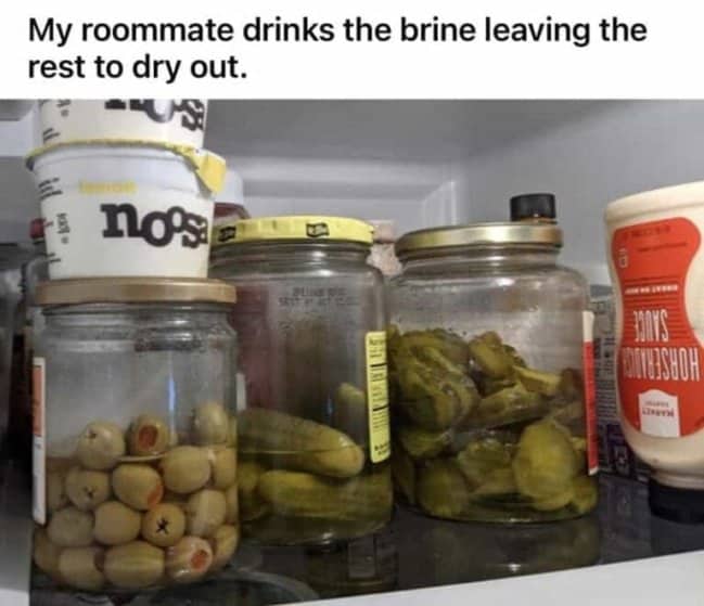 Jars of pickles and olives in a fridge shelf where the liquid brine has been drained.