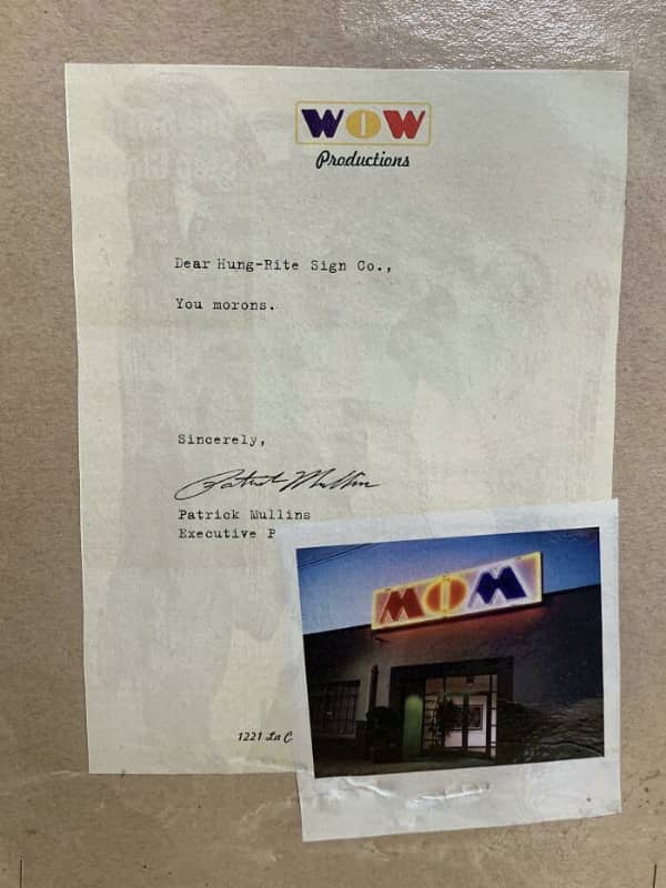 A formal complaint letter to a sign company that hilariously hung a WOW Productions logo upside down.