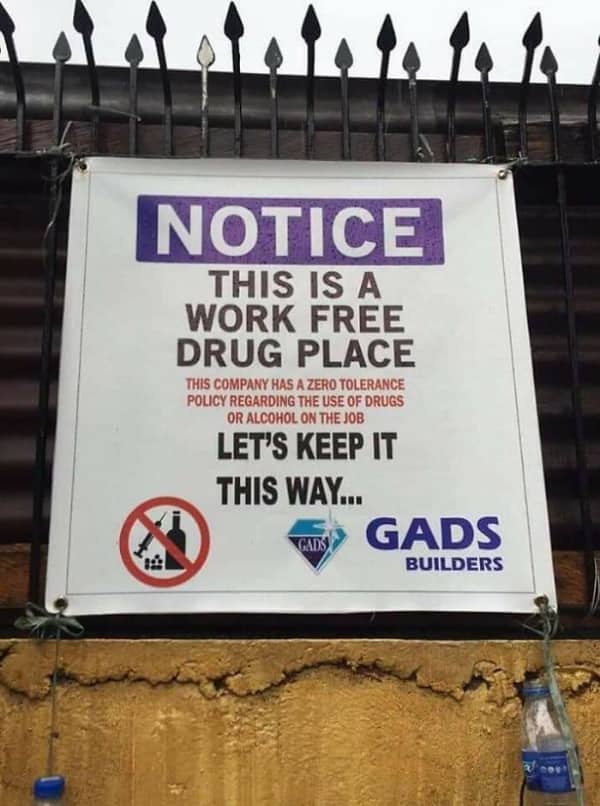 A construction site banner stating this is a work free drug place with mixed up words.