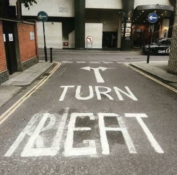 A confusing street stencil trying to spell right turn but creating a messy jumble of letters.