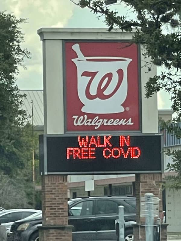 A digital Walgreens pharmacy marquee sign reading walk in free covid due to missing text space.