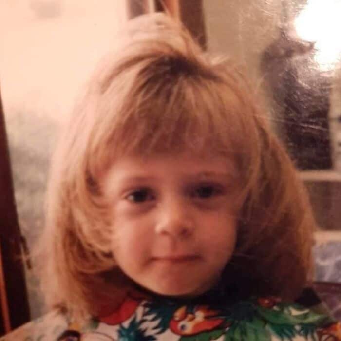Close-up of a toddler girl with massive, fully blown-out feathered hair.
