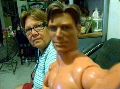 A woman posing next to a plastic male action figure doll held close to the camera.