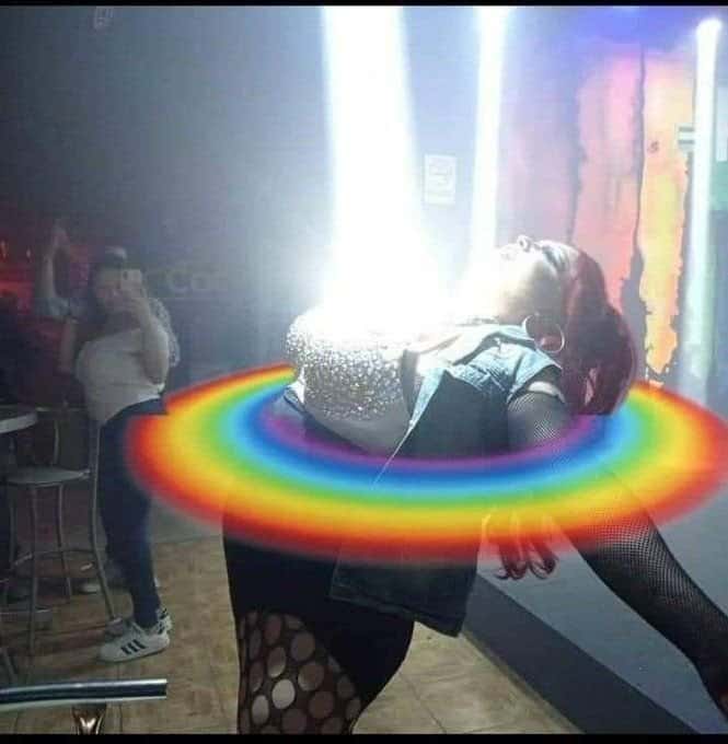 A woman at a venue with a bright light beam and a rainbow overlay effect.