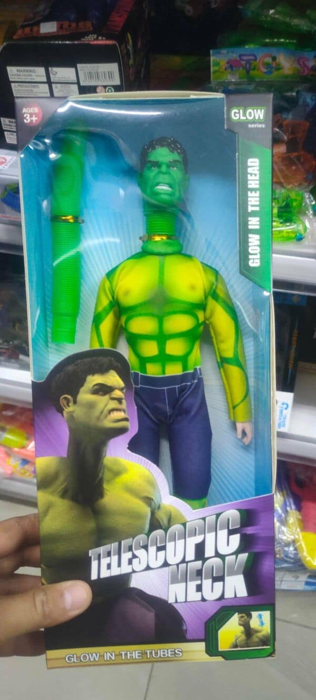 An absurd classic meme showcases a bootleg green superhero action figure packaged in a box with an incredibly long, telescopic plastic accordion neck.
