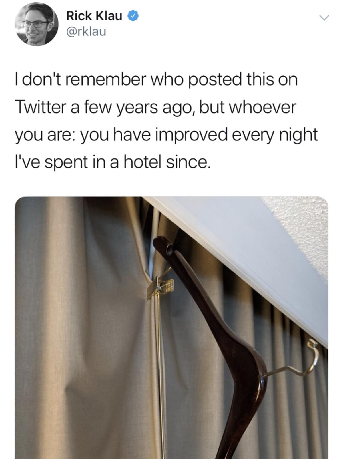 A brilliant life-hack photo functioning as a classic meme showing a wooden hotel clothes hanger with pants clips being used to clamp curtains tightly shut to block out early morning sunlight.