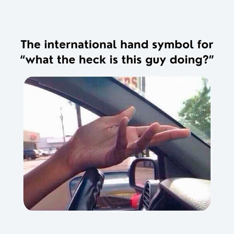 A universal road-rage gesture driving meme capturing a driver's open, upward-facing hand inside the cabin to demonstrate the international gesture for questioning another motorist's absolute lack of driving skill.