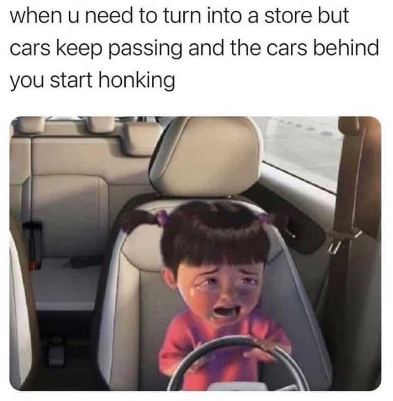 A high-stress driving meme featuring Boo from Monsters Inc edited behind a car steering wheel crying hysterically, capturing the absolute panic of waiting to turn into a store while cars honk behind you.