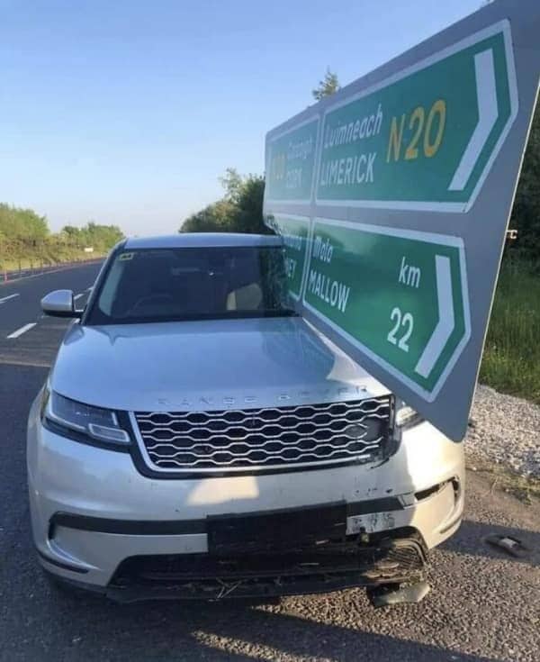 A silver Range Rover SUV crashed directly into a large green highway traffic sign.