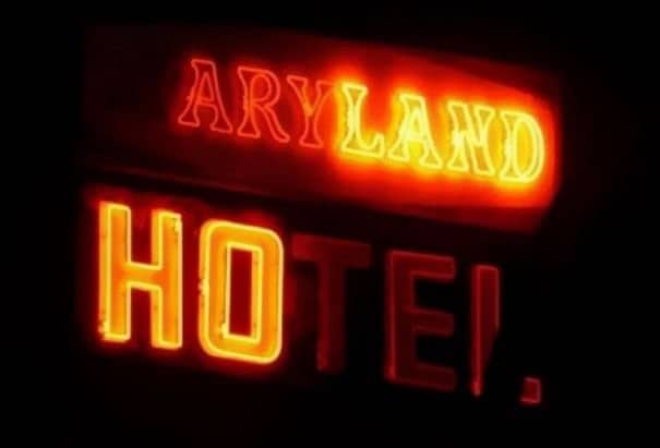 Glitching Maryland Hotel neon sign at night reading only ARYLAND HOTEL with spelling error.