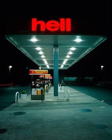 A broken neon sign on a Shell gas station reading only the word hell.
