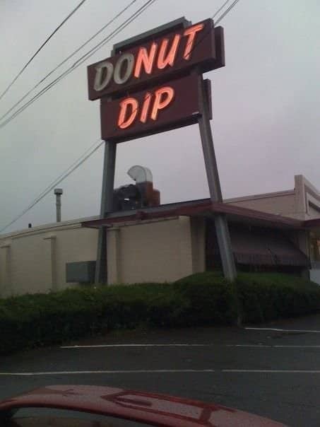 A broken Donut Dip neon sign reading DOUT DIP outside a shop.