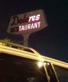 A broken Dolores Restaurant neon sign glowing at night to read Dolores ESTAURANT.