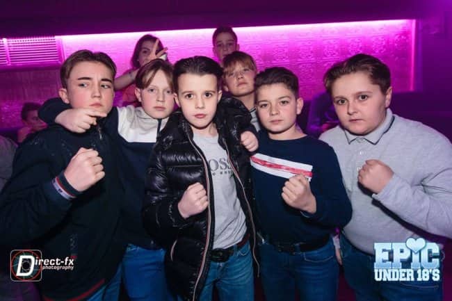 Group of young boys aggressively posing with raised fists at an under-18 disco.
