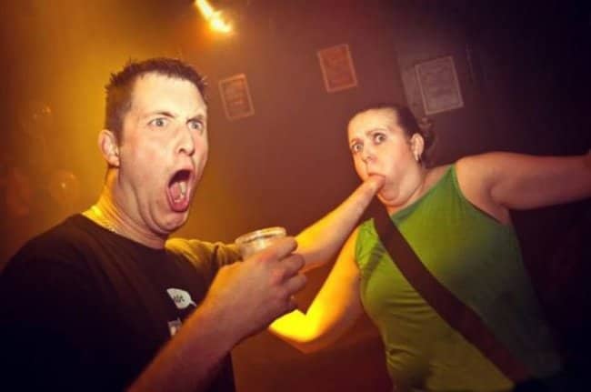 Man looking wide-eyed and shocked while a woman panics in a dark club.