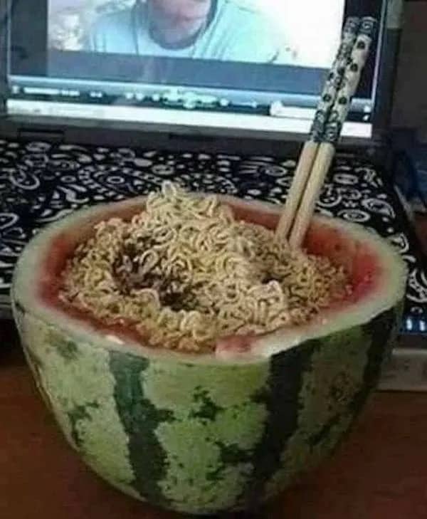 Instant ramen noodles served directly inside a hollowed-out watermelon half with chopsticks inserted.