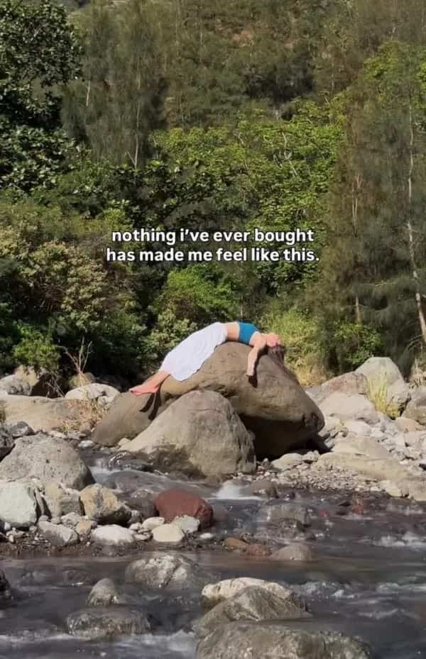 Funny memes image of a woman relaxing dramatically across a large boulder by a river.