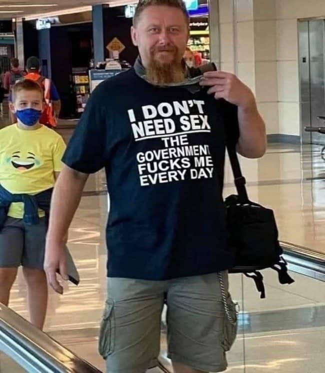 Man at airport wearing a government protest joke shirt as part of funny outfits.