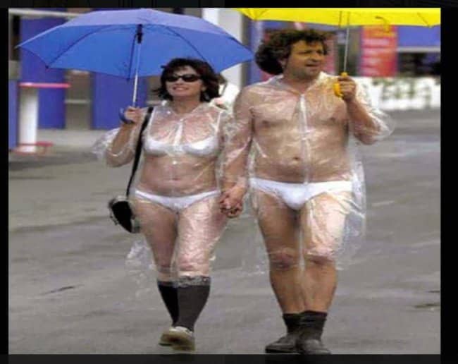 Couple walking in rain wearing clear plastic ponchos over white undergarments in funny outfits.
