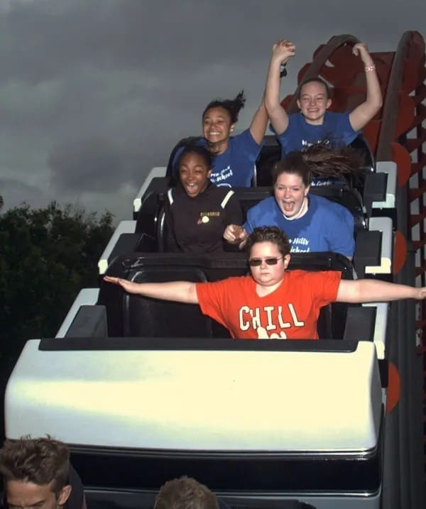 A boy wearing sunglasses and a shirt that says CHILL looking totally deadpan on a rollercoaster.