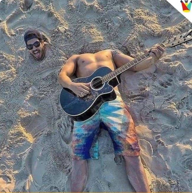 An optical illusion of a headless man playing guitar next to a buried head.