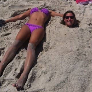 An optical illusion on a beach showing a disembodied bikini body next to a head.