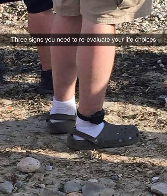 This viral photo in the meme dump focuses on a person's lower legs wearing brown Crocs clogs with white socks and a prominent electronic ankle monitor, captioned as a sign to re-evaluate life choices