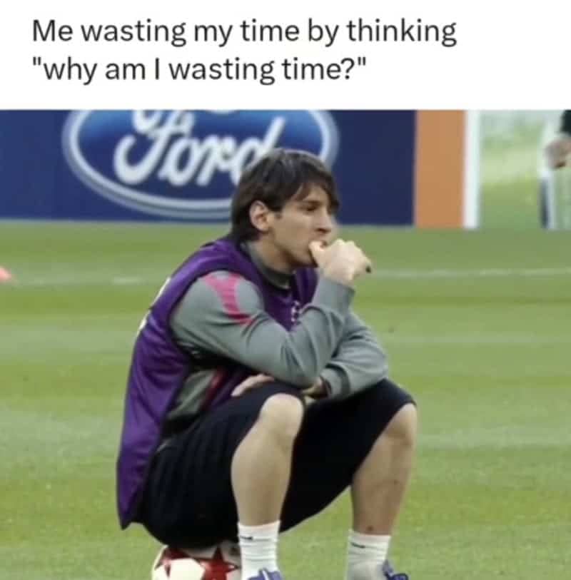 Lionel Messi squatting on a soccer ball during practice, deep in thought about wasting time.