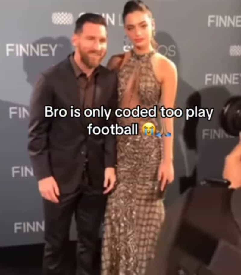A blurry photo of Lionel Messi standing awkwardly next to a tall model at an event.