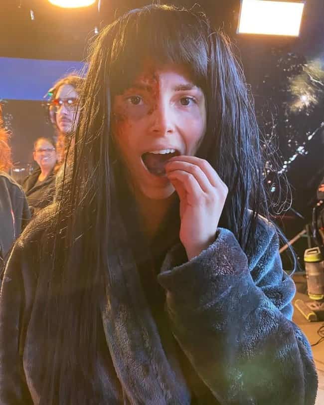 Behind the scenes photo of actress eating snacks with bloody makeup in Obsession memes.