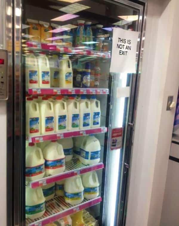 Grocery store milk display fridge door featuring a sign stating this is not exit.