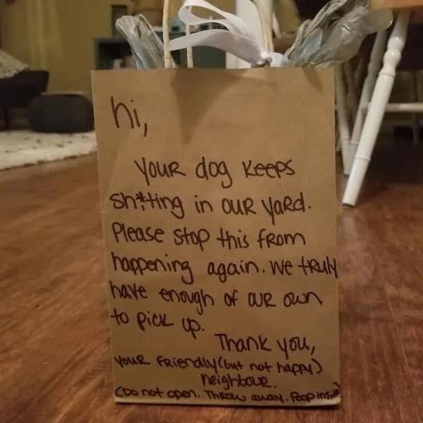 Brown paper gift bag with a handwritten note about dog poop inside left for a neighbor.