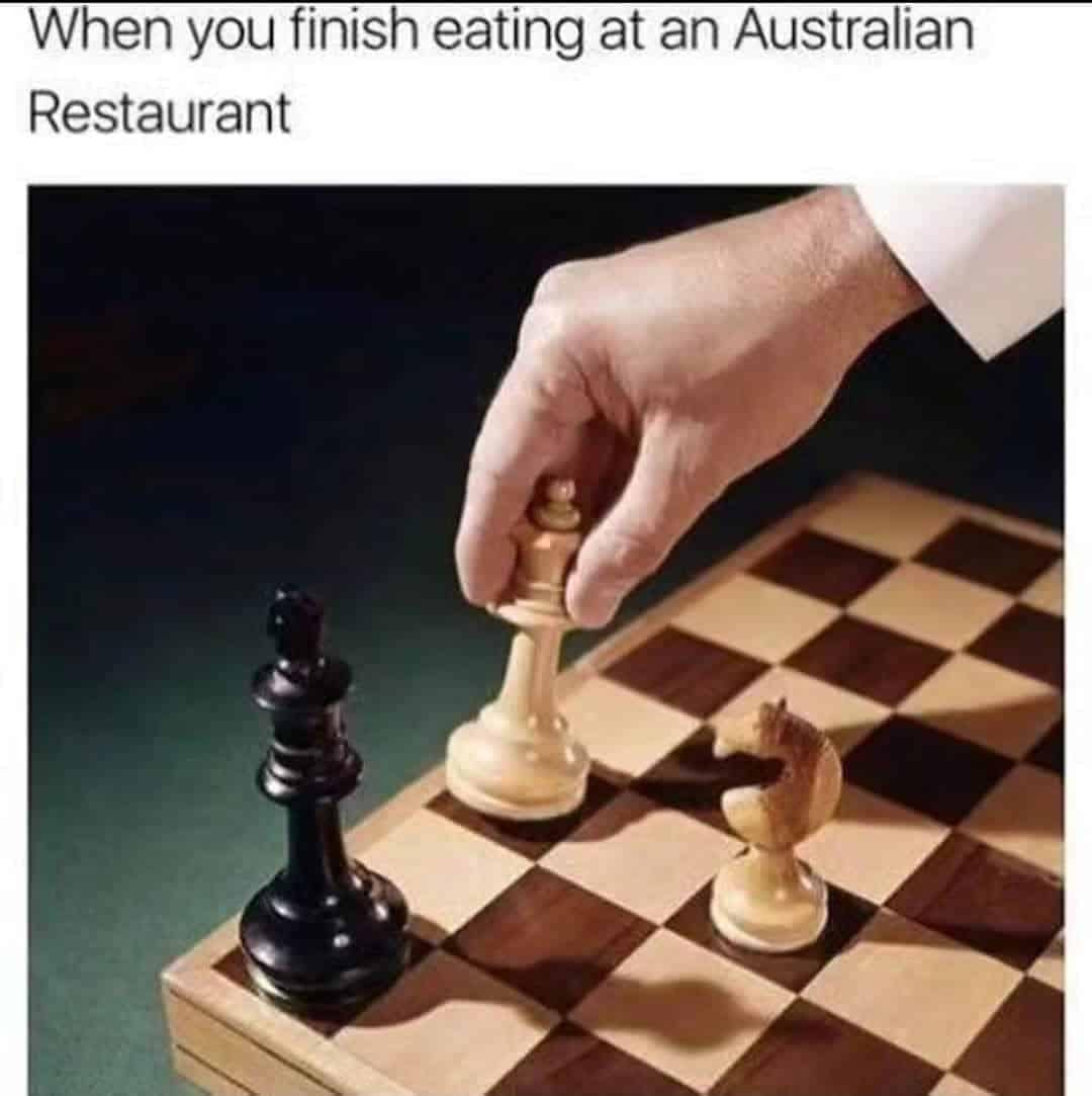 A clever strategic punny meme showing a hand executing a winning checkmate move on a wooden chessboard, framed as the universal, literal sign for finishing up a meal at an Australian restaurant.