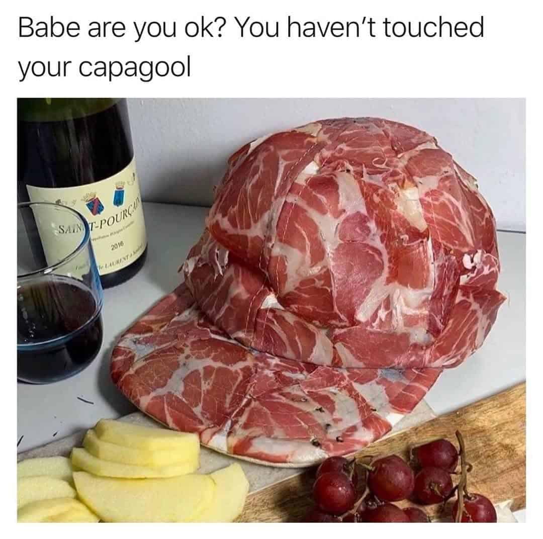 An amusing punny meme showcases a charcuterie board setup featuring a sports baseball cap constructed entirely out of sliced capicola deli meat next to a wine bottle.