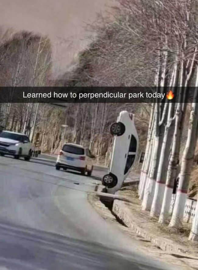 This literal car crash turns into a road trip meme showcasing a white sedan wedged completely vertically nose-first inside a narrow concrete roadside drainage ditch.