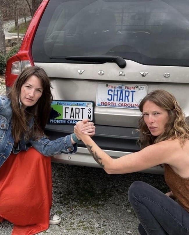 An epic road trip meme showcases two women shaking hands behind a Volvo featuring custom vanity license plates that read FART and SHART.